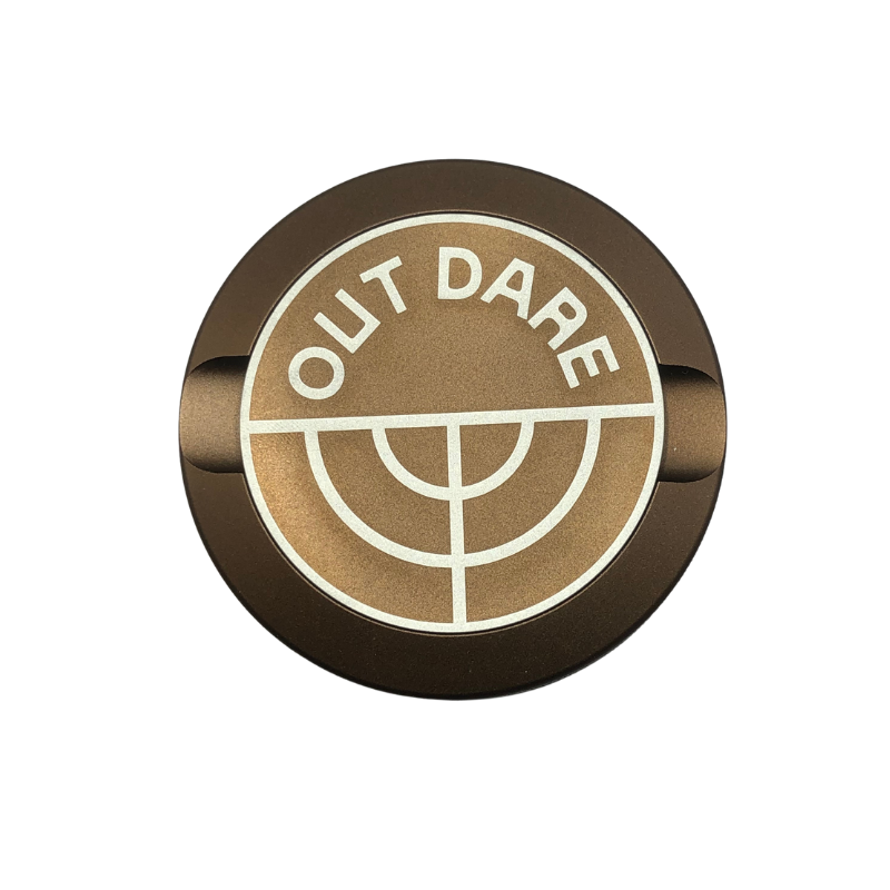 Detail close-up of the brown Outdare Metal Can showcasing a circular logo with 'OUT DARE' text.