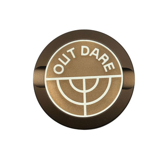 Detail close-up of the brown Outdare Metal Can showcasing a circular logo with 'OUT DARE' text.